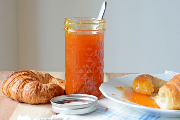 apricot jam on a croissant with a jar of preserves