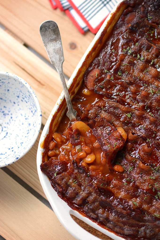 A spoon resting in a dish full of Potluck-Perfect Baked Bean Casserole