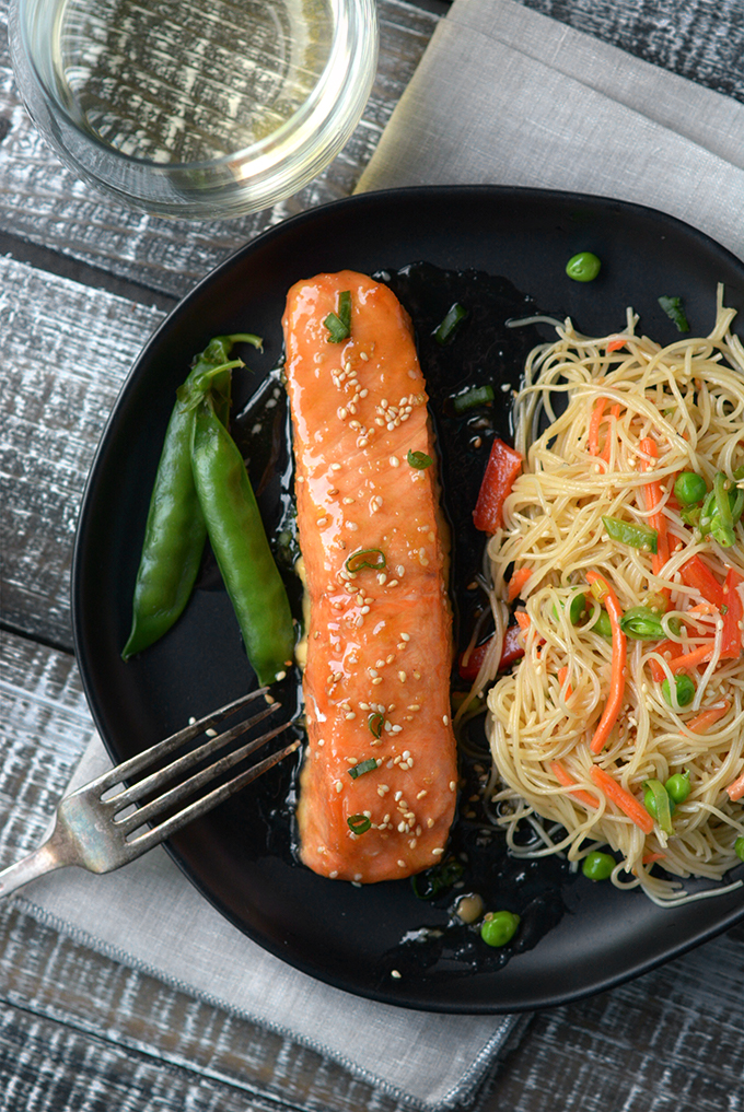 Oven Baked Sesame Salmon on a black plate with sesame noodle salad and sugar snap peas