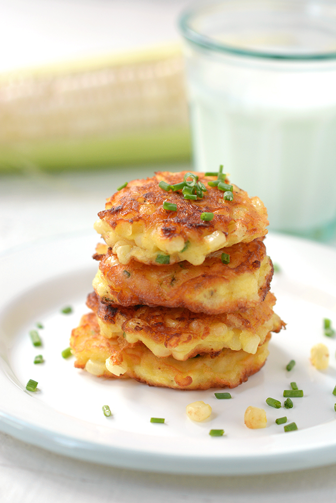 Closeup of corn fritters with chives stacked on a plate.