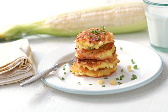 Corn fritters with chives stacked on a plate