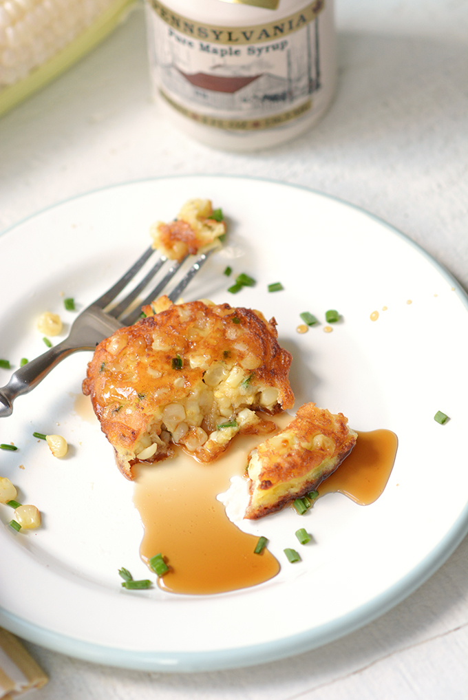 Corn fritters with chives on a plate with maple syrup