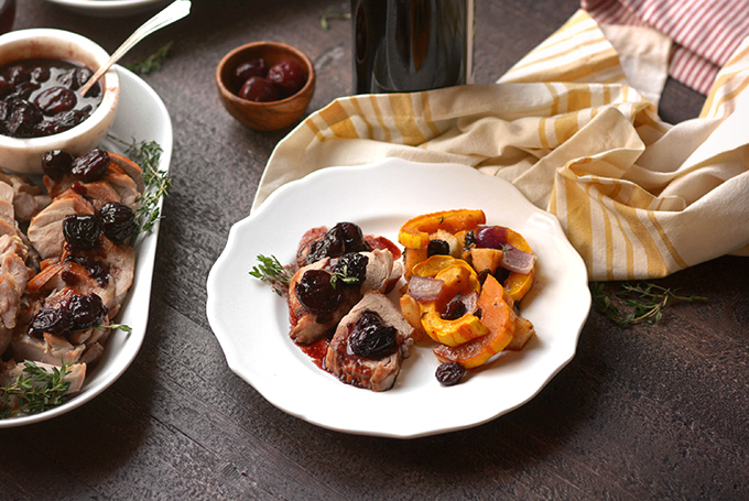 Pork tenderloin with cherry sauce and delicata squash on a plate