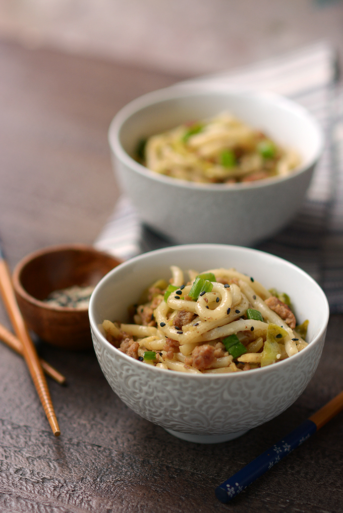 Pork and Cabbage Udon Noodles with Black Sesame Seeds in a bowl on a table