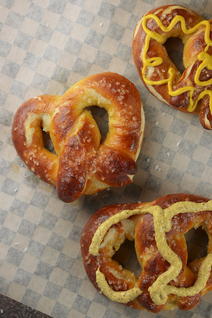 Homemade soft pretzels with mustard on a sheet of parchment paper