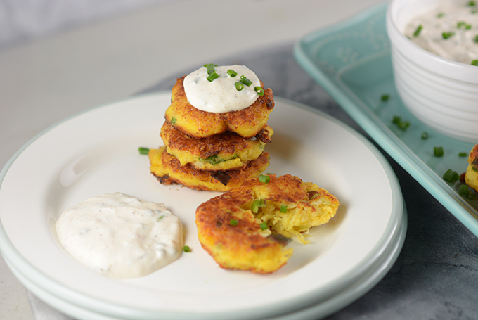 Spaghetti squash fritters on a small appetizer plate with a dollop of sour cream and chives.